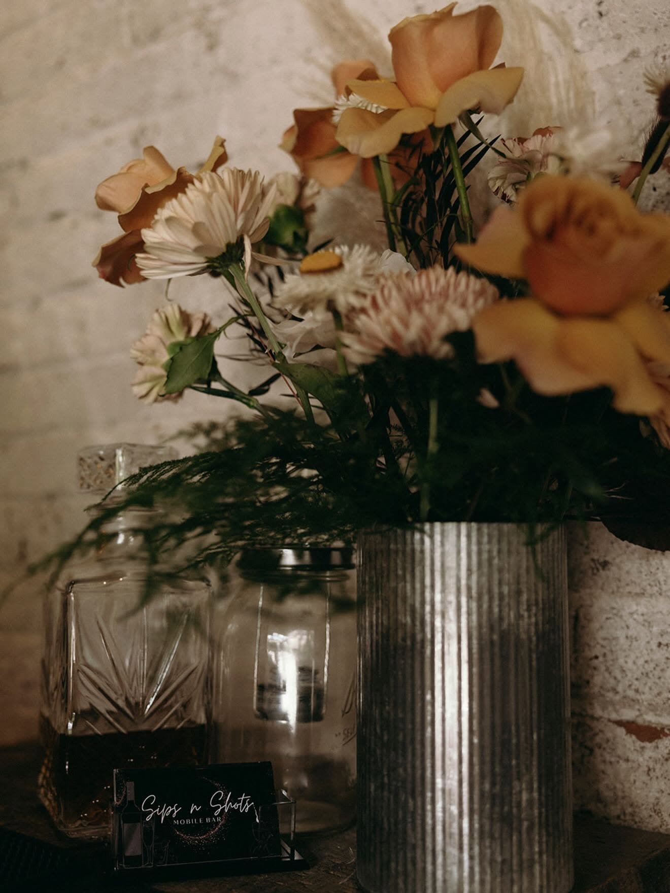 Fresh flowers and a Sips & Shots business card at an event bar
