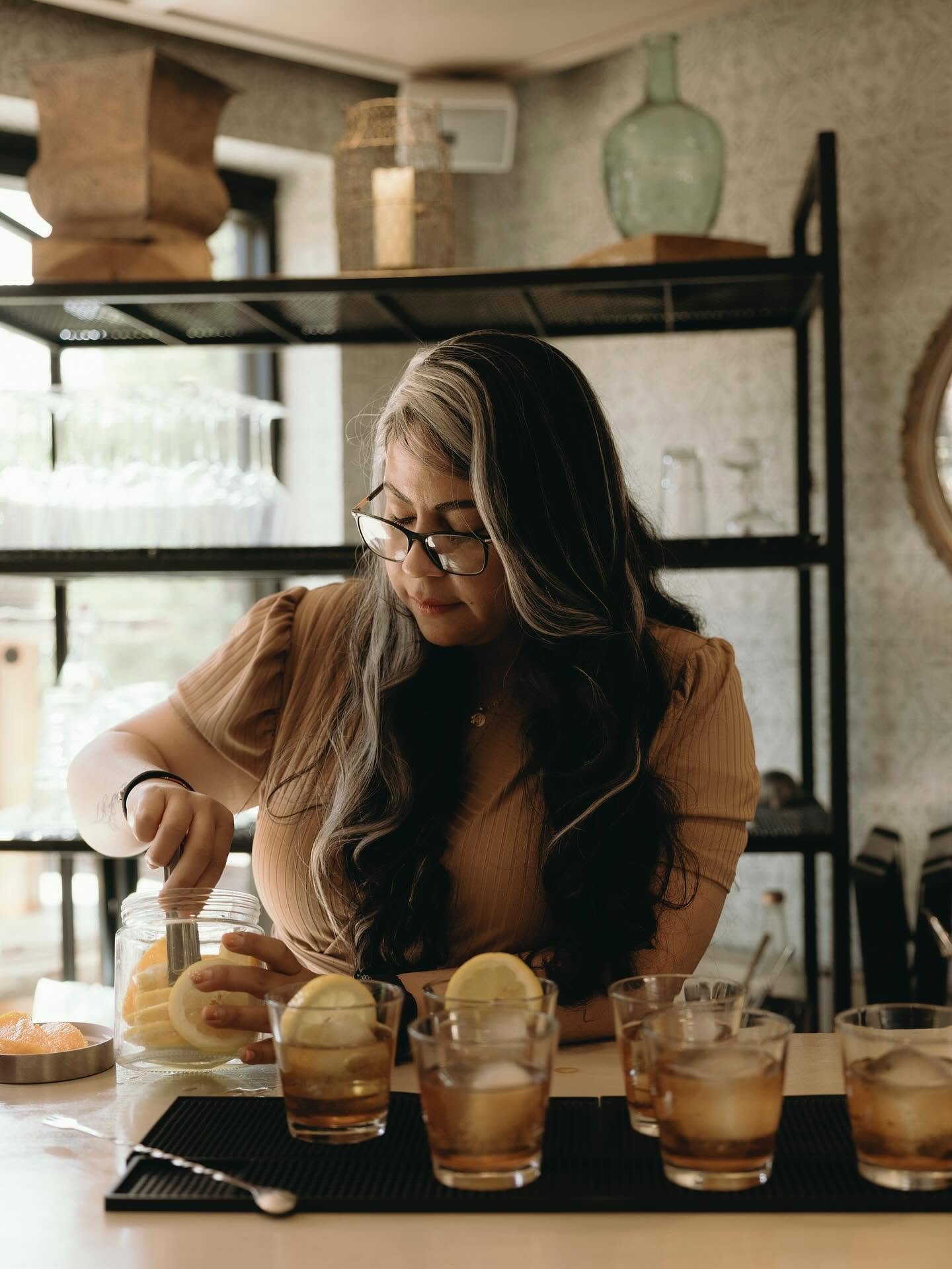 Sips & Shots owner garnishing a row of old fashioneds